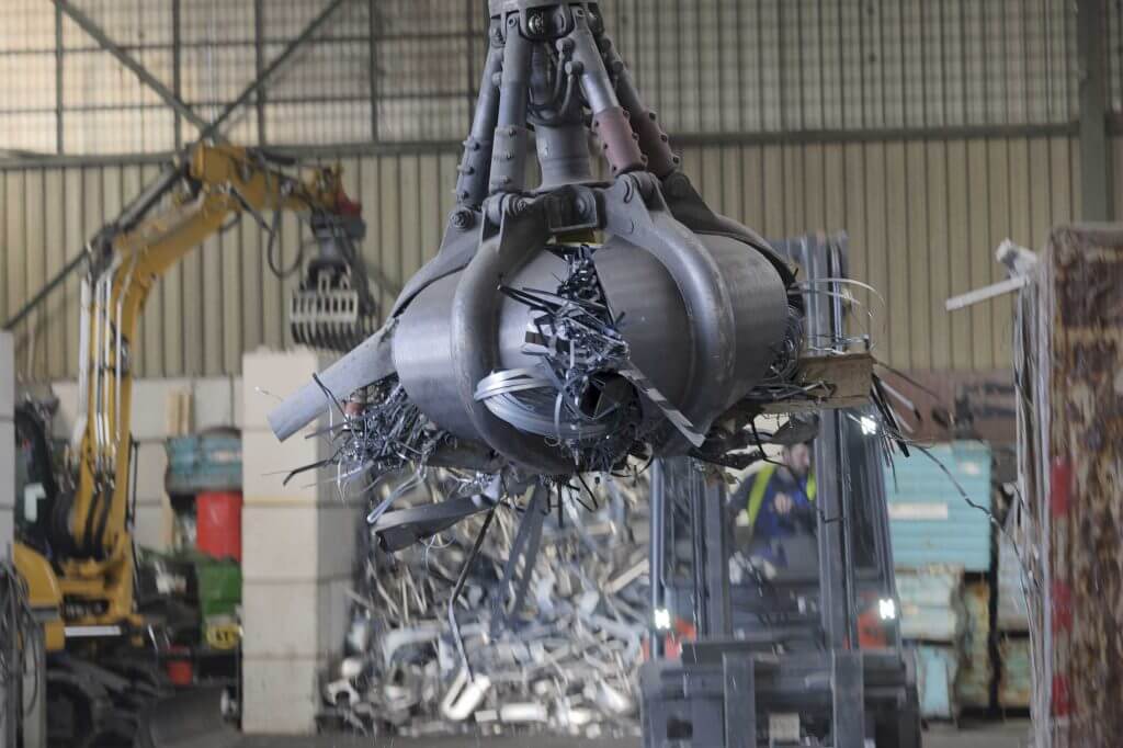 plier crane grabbing scrap in a scrap metal recycling plant
